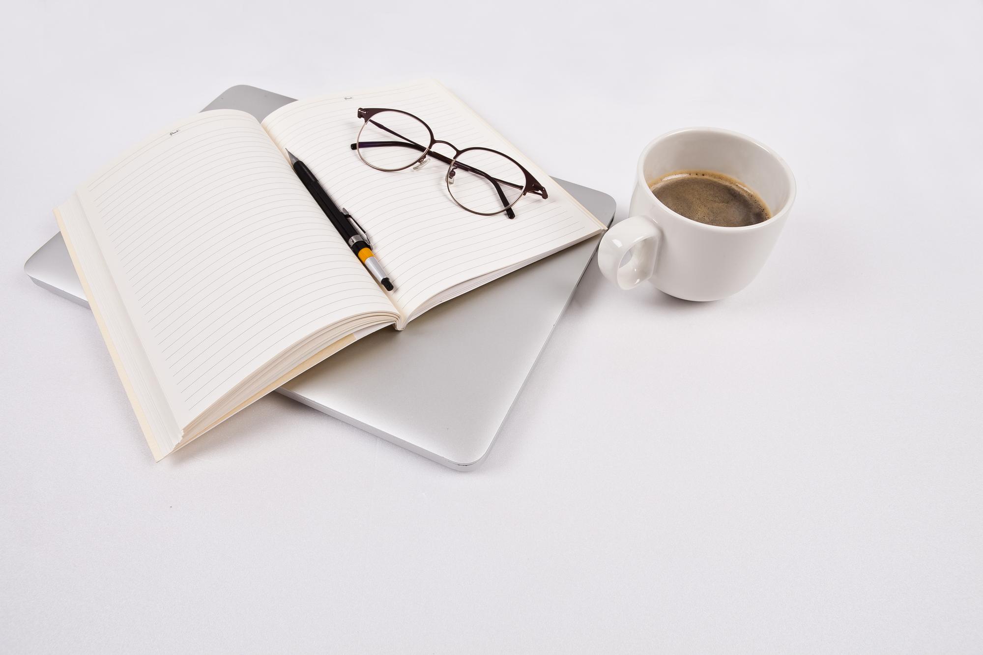 Kaffeetasse neben geöffnetem Notizbuch